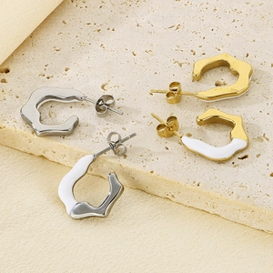 Irregular C-shaped earrings in gold and silver finish on elegant beige stone
