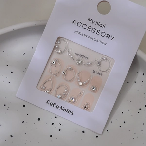Detailed view of silver-framed pearl and rhinestone nail charms on display card MJ-062