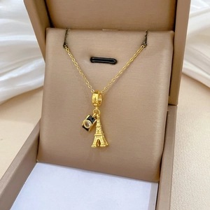 Detail of gold necklace featuring Eiffel Tower and mini camera charms with zircon stone