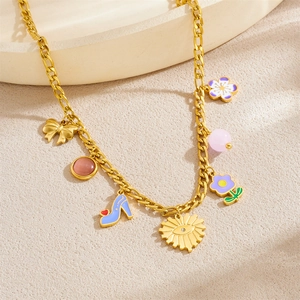 Gold NK link necklace with colorful charms like bow, sun, and flower on a textured surface
