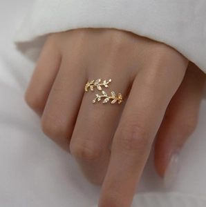 Close-up of golden leaf-shaped open ring with clear zircons on model's finger