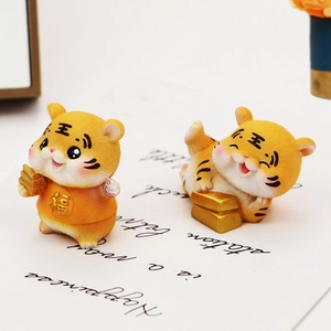 Close-up of two cute cartoon tiger figurines with gold ingots for car or desk decor