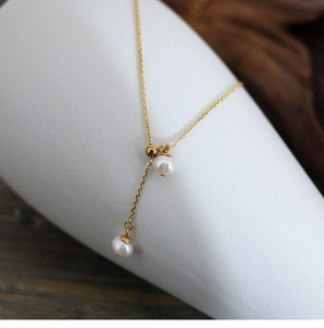 Detail of adjustable gold Y-necklace with elegant natural freshwater pearls on white stand