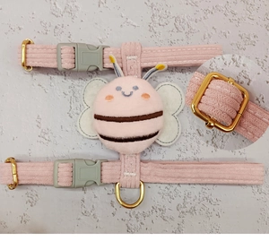 Detail of pink corduroy cat harness with plush bee doll and sturdy metal buckle closure