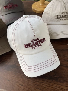 Detail shot of multi-color baseball caps with letter embroidery on a wood surface