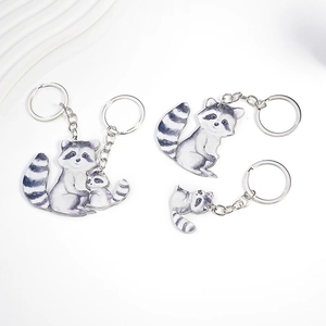 Detailed view of three acrylic raccoon keychains with watercolor art and silver rings