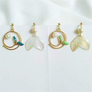 Detail of asymmetric whale tail earrings with pearls and colorful enamel finish