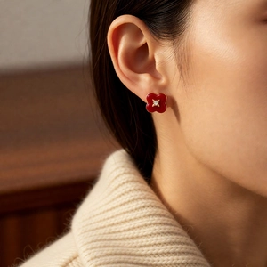 Close-up of vintage gold flower earring with red enamel and diamond center on ear