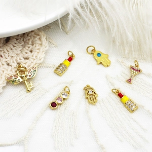Detailed macro view of 18K gold-plated charms with zircons on lace and feather base