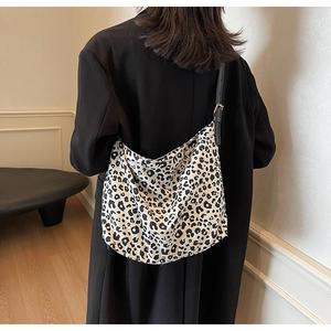Close-up of leopard print tote bag styled with a black blazer on a model's shoulder