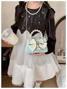 Girl's mint green houndstooth bag with pearl bow and handle held by a model