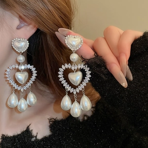 Dettaglio di orecchini a cuore in argento con perle finte bianche e strass scintillanti