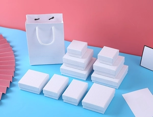 Detailed macro view of minimalist white litchi textured jewelry boxes and matching gift bags