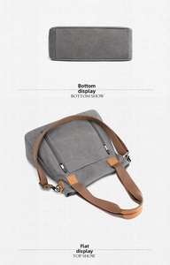 Detail of gray canvas tote with brown straps, bottom structure and metal zipper pockets