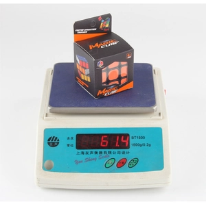 Digital scale showing a 61.4g weight for the classic black 3x3x3 puzzle cube in packaging