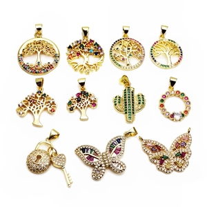 Flat lay of diverse gold-plated brass pendants with colorful zircon butterfly and magic tree
