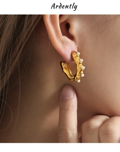 Macro view of gold U-shaped hammered texture earrings with elegant micro pearl accents