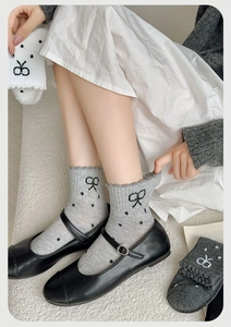 Detailed texture of cotton socks with black polka dots, ruffle cuffs and bow patterns