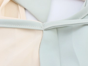 Close-up of color-block fabric stitching and texture on the beige and mint dress
