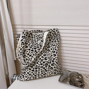 Detail of leopard print canvas tote bag featuring durable white webbing handles and a logo tag