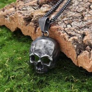 Retro stainless steel skull pendant with chain on mossy bark for a vintage biker style