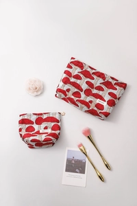 Detail of red mushroom pattern fabric pouches with floral zipper puller and brushes