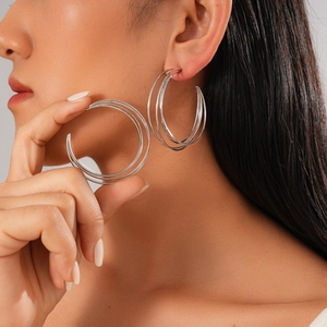 Chic silver multi-layer geometric C-shaped earrings worn by a model in a studio shot