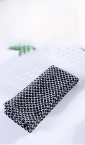 Close-up of double-sided exfoliating bath towel with houndstooth texture and reinforced edges