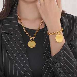 Close-up of golden O-chain necklace and bracelet set with round charms and T-bar toggle