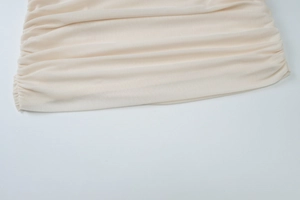 Detailed macro view of the beige mesh fabric with intricate pleated texture and soft ruching