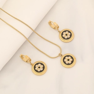 Golden necklace and earrings set featuring black circular pendants with pearl flower design