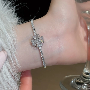 Close-up of elegant silver clover bracelet with sparkling zircons on a woman's wrist