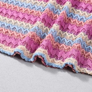 Détail macro du tissu tricoté à vagues bohème aux tons pastel rose, bleu et crème