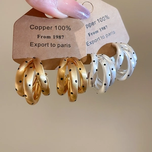 Dettaglio di orecchini a cerchio a C in oro 18k e argento con pois neri alla moda