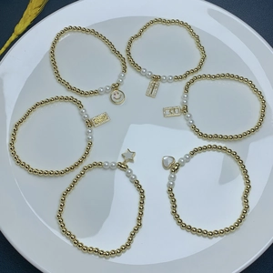 Close-up of golden beaded stretch bracelets featuring cross, heart, and star charms