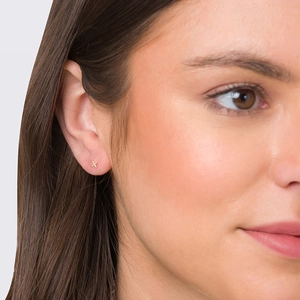 Elegant gold S925 sterling silver cross stud earring worn by a model in a close-up view