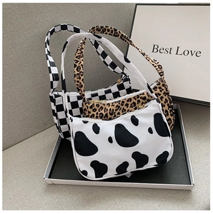 Close-up of three hobo bags featuring cow, leopard, and checkerboard prints in a display box