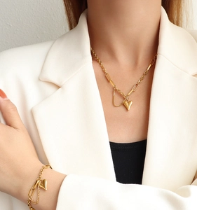 Close-up of gold heart pendant necklace and matching bracelet set on white blazer