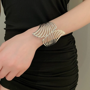 Detailed close-up of wide silver flowing metal heart wing cuff bracelet on model
