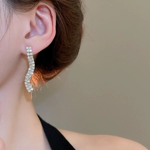 Close-up of elegant wavy drop earrings with double-row sparkling rhinestones on model