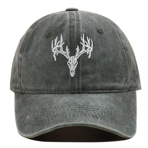 Close-up of white embroidered deer skull design on washed grey cotton baseball cap