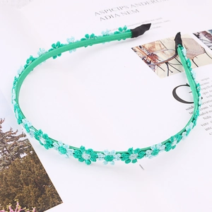 Close-up of green satin headband with blue and green embroidered daisy floral details