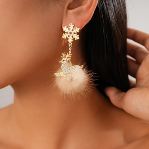 Close-up of model wearing Christmas reindeer earrings with snowflakes and beige fur balls