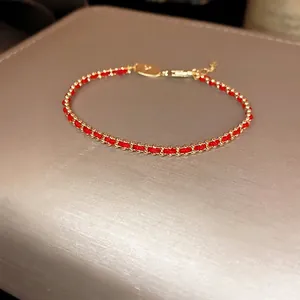 Handwoven red rope bracelet with gold-plated beads and adjustable lobster clasp