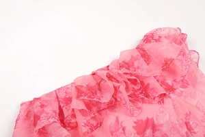 Close-up of pink floral chiffon fabric with ruffled edge and layered texture details