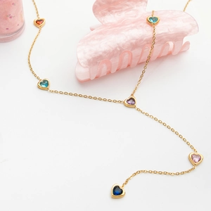 Detail view of gold Y-chain necklace with colorful heart stones on white background