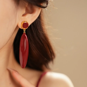 Gros plan de boucles d'oreilles ovales en émail bordeaux avec bordure dorée chic