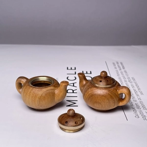 Green sandalwood lotus sachet teapot pendant with brass accents on white paper
