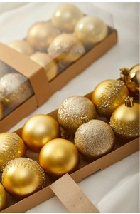 Detail of gold Christmas ornaments showing glossy, matte, and glitter textures in a gift box