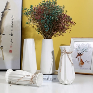 Modern white ceramic vases in various geometric shapes with natural twine decorations